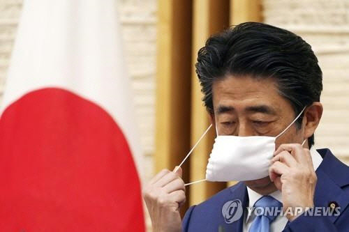 아베 신조(安倍晋三) 일본 총리가 5월 4일 일본 총리관저에서 기자회견을 하기 위해 마스크를 벗고 있다.   EPA=연합뉴스